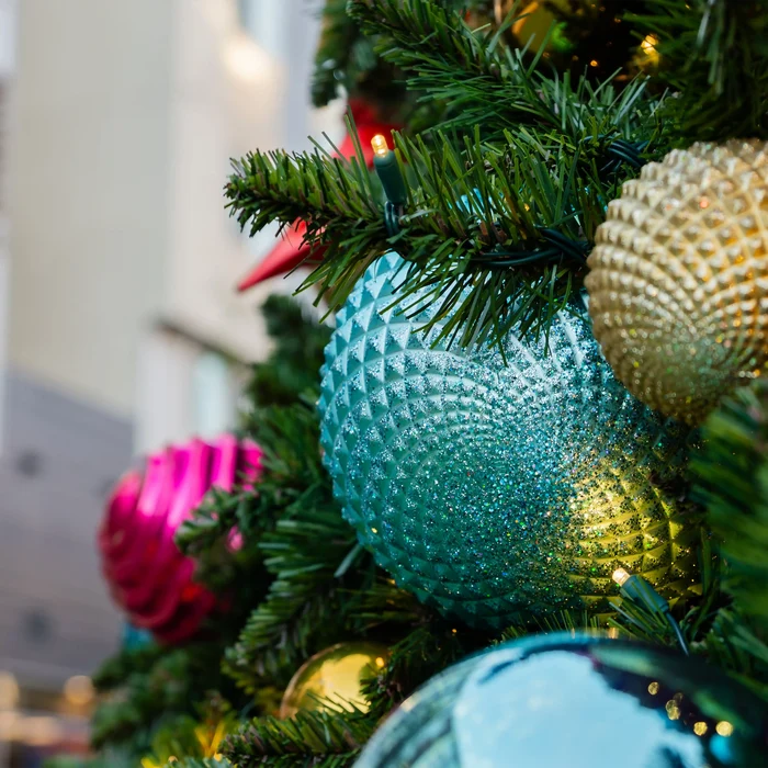 Close-up of a Christmas tree with colorful ornaments and blurred lights in the background