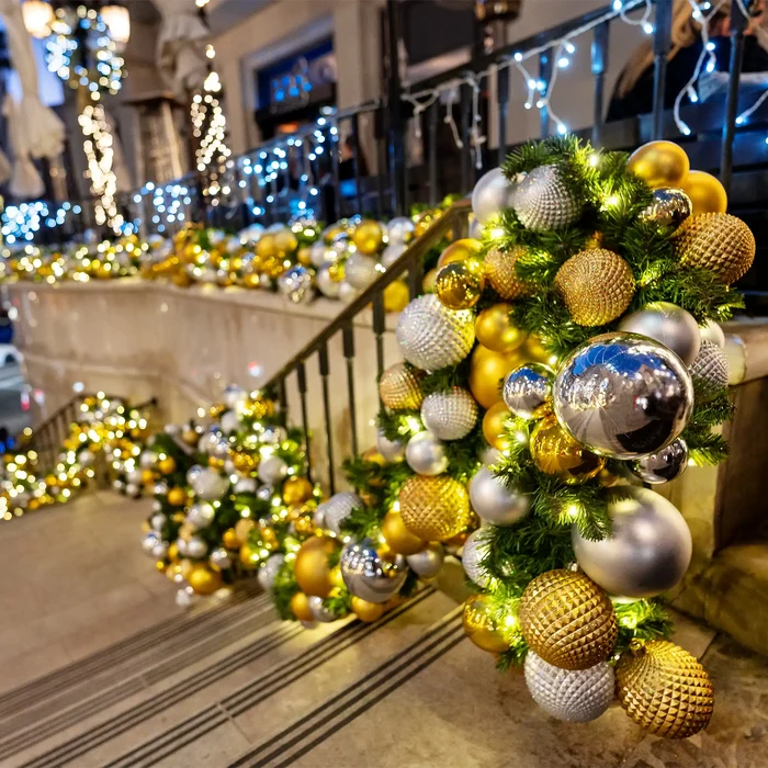 Decorative Christmas wreaths with gold, silver, and white ornaments on a staircase.