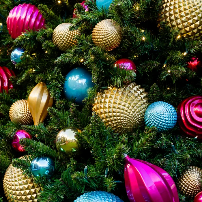 Close-up of a Christmas tree with colorful ornaments including gold, blue, and pink.