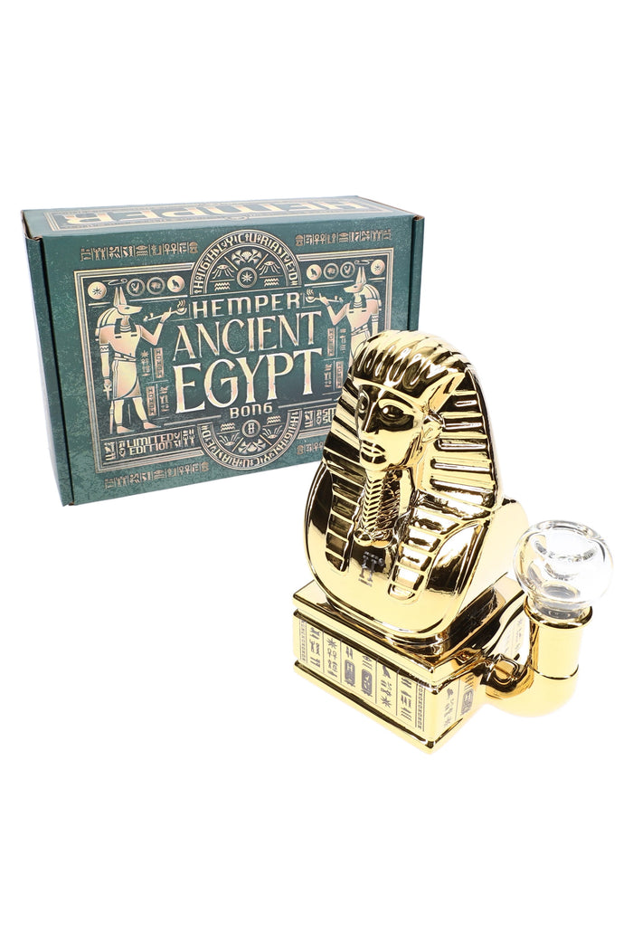 Gold Ancient Egypt glass bong standing beside teal retail box, showing pharaoh bust design and hieroglyphic plinth.