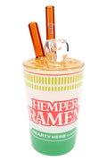7-inch Hemper ramen cup glass bong with yellow noodle lid, clear bowl and amber chopstick mouthpieces on white.