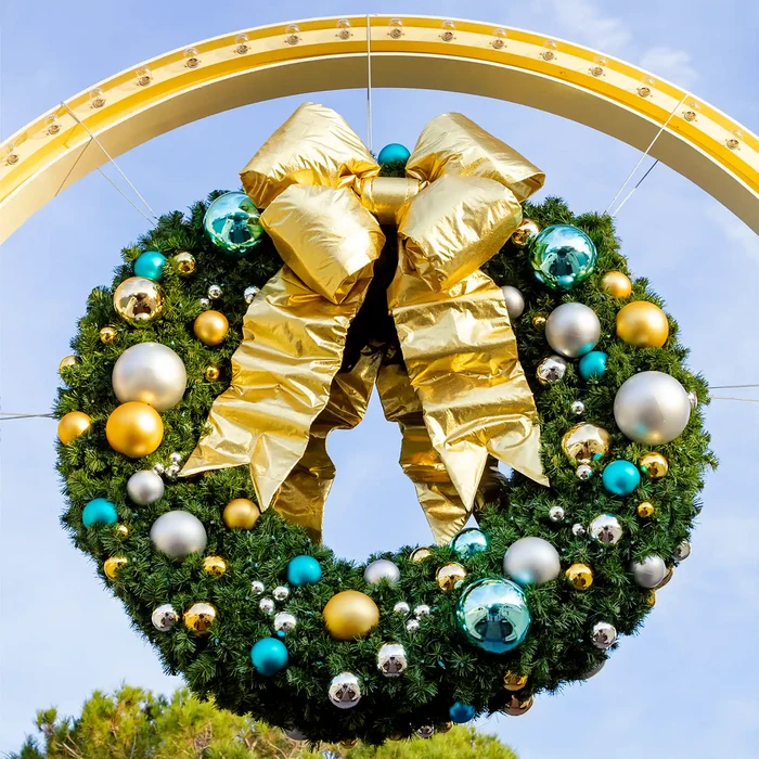 Large shiny teal, gold, and silver shatterproof ornaments on a commercial Christmas wreath